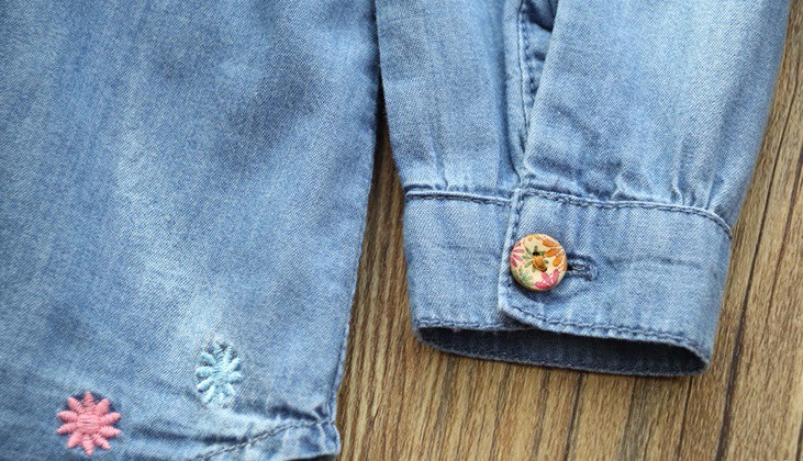 sinine teksakleit lilledega tikitud detailidega ja nööbiga varrukas